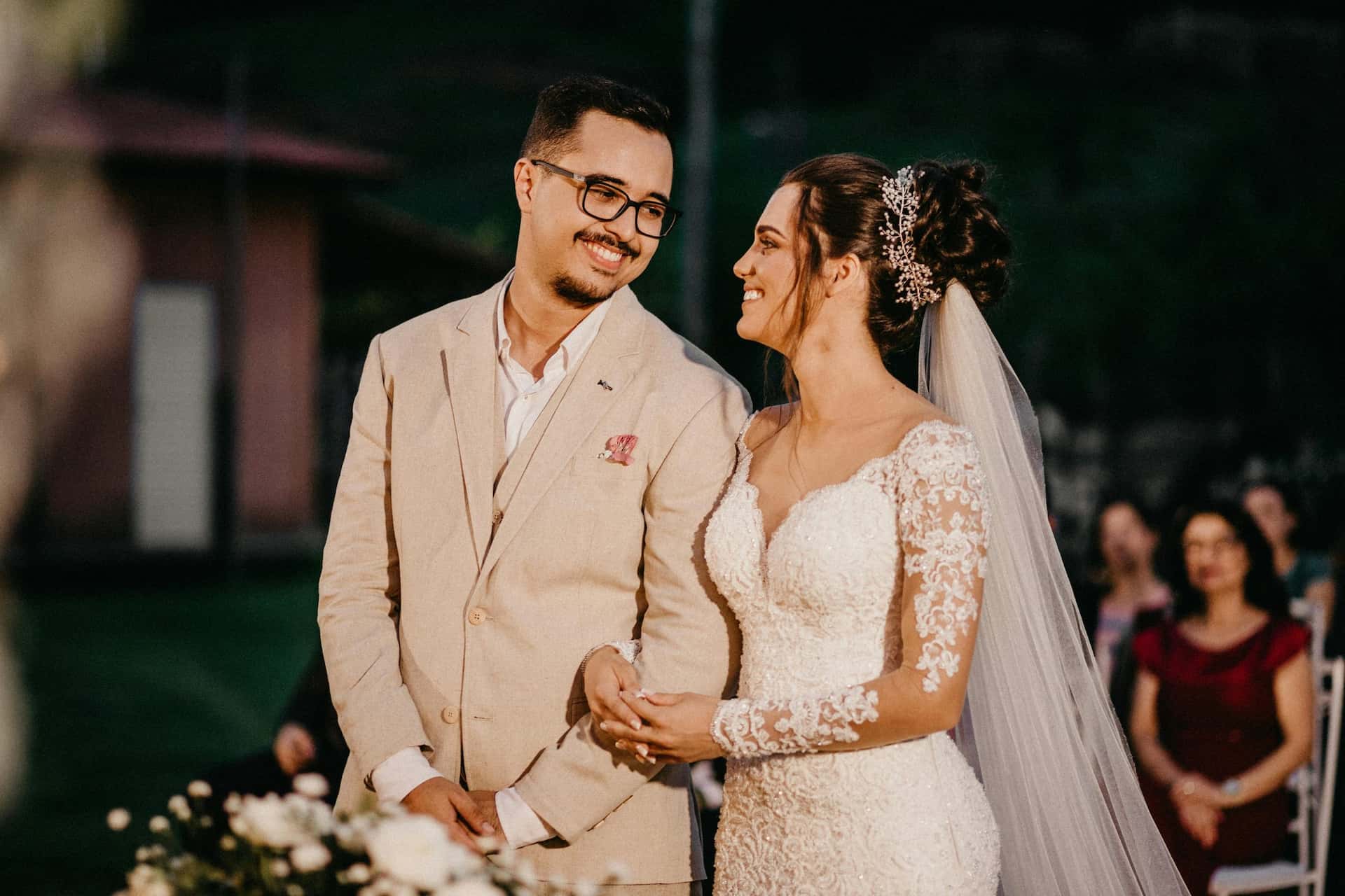 Elegancka fotografia ślubna w Katowicach – Pan Młody w beżowym garniturze i Panna Młoda w koronkowej sukni patrzący na siebie, reportaż ślubny Śląsk.