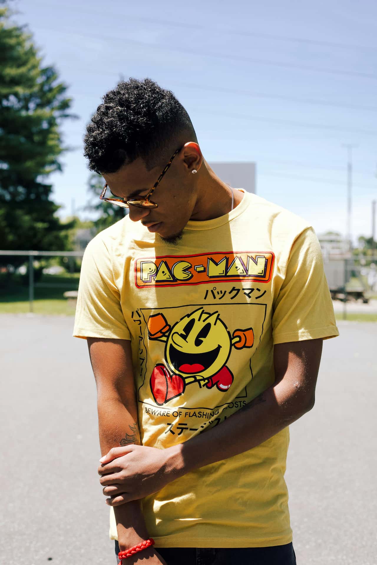 Męska sesja portretowa Katowice – młody mężczyzna w żółtym t-shircie z nadrukiem Pac-Man i okularach przeciwsłonecznych, letnia fotografia lifestyle na zewnątrz, Śląsk.